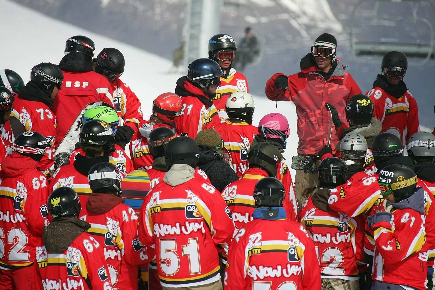 Snowjam-riders luisteren naar de briefinggever met muts op de berg